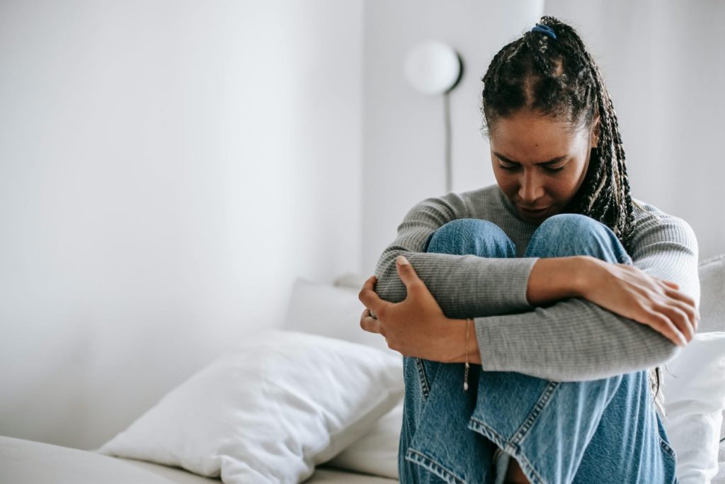 A woman sitting with her head down, symbolizing breaking negative thought patterns through CBT therapy at BrightMind Wellness in Harrisburg and Philadelphia.