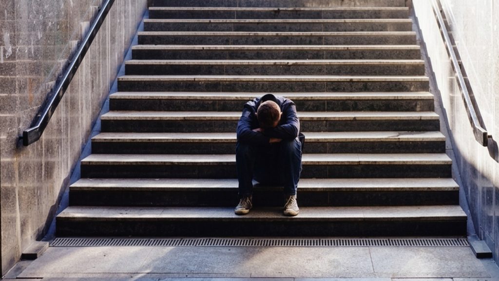 Person sitting on stairs with head down feeling lonely in a new country
